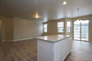 Kitchen with dark wood-style floors, baseboards, a kitchen island, white cabinets, and open floor plan