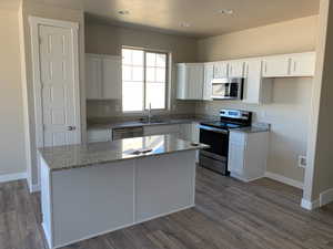 Kitchen featuring a sink, appliances with stainless steel finishes, a center island, and white cabinetry