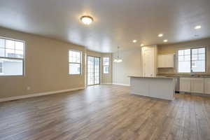 Kitchen with baseboards, a center island, stainless steel dishwasher, and wood finished floors