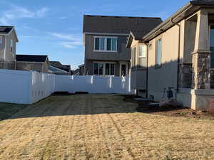 Rear view of property featuring stucco siding, a lawn, and fence