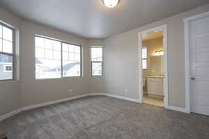 Unfurnished bedroom featuring connected bathroom, baseboards, and carpet