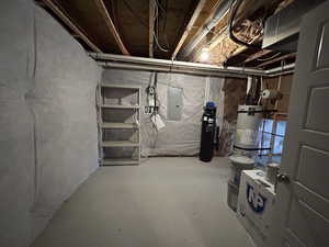 Unfinished basement featuring electric panel and strapped water heater