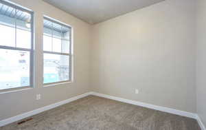 Spare room with visible vents, carpet flooring, and baseboards