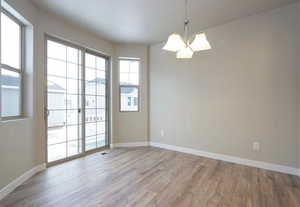 Unfurnished room with baseboards, an inviting chandelier, and wood finished floors