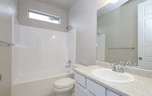 Bathroom featuring toilet, vanity, and shower / tub combination