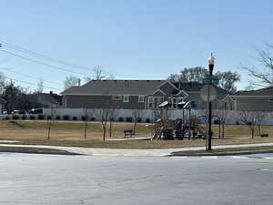 View of front of house featuring a front lawn, fence, playground community, and a residential view