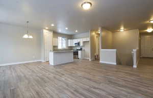 Kitchen featuring light wood finished floors, open floor plan, white cabinetry, and stainless steel appliances