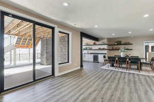 Dining room with baseboards, light wood-style flooring, recessed lighting, wine cooler, and a textured ceiling