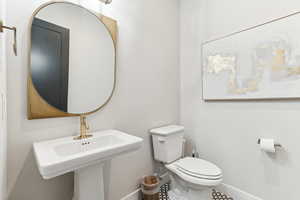 Half bath with toilet, baseboards, and a sink
