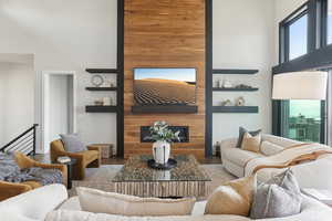 Living room featuring a glass covered fireplace, a high ceiling, and wood finished floors