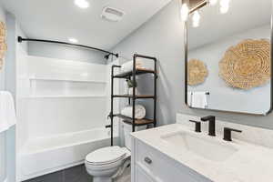Bathroom featuring visible vents, shower / bathtub combination, toilet, and vanity