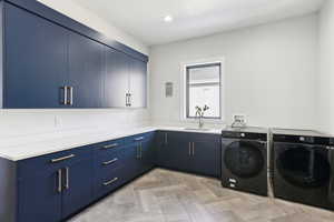 Laundry area with separate washer and dryer, cabinet space, and a sink