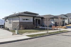 Prairie-style home with concrete driveway, a garage, a front yard, and stucco siding