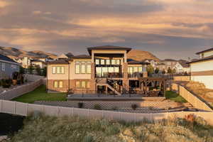 Back of property at dusk featuring a fenced backyard, a mountain view, a patio, and stairs