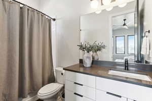 Bathroom featuring connected bathroom, toilet, vanity, and a ceiling fan