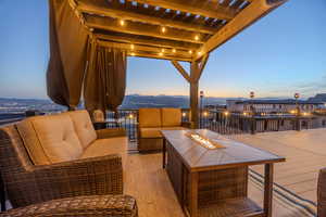 Deck at dusk featuring a pergola, a mountain view, and an outdoor living space with a fire pit