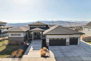 Prairie-style house with stone siding, a mountain view, driveway, and a garage