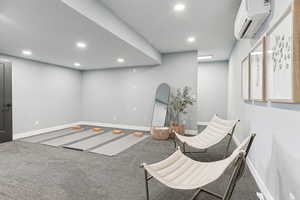 Sitting room featuring recessed lighting, baseboards, and a wall unit AC