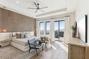 Bedroom featuring access to exterior, recessed lighting, wood finished floors, and a raised ceiling