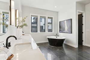 Bathroom with a freestanding tub, plenty of natural light, and baseboards