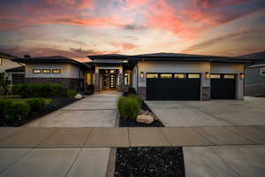 Prairie-style home with stone siding, a garage, concrete driveway, and stucco siding