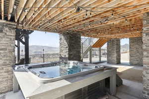 View of patio / terrace with a mountain view, a hot tub, and stairs