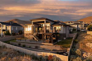 Back of house at dusk featuring a fenced backyard, a deck with mountain view, stairs, stucco siding, and a residential view