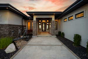 View of exterior entry with stucco siding and stone siding