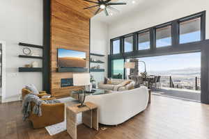 Living area with wood finished floors, a high ceiling, a fireplace, baseboards, and ceiling fan