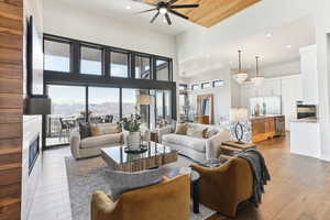 Living area with wood finished floors, a ceiling fan, a fireplace, recessed lighting, and a towering ceiling