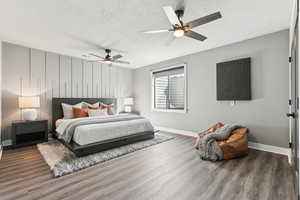 Bedroom with a textured ceiling, a ceiling fan, baseboards, and wood finished floors