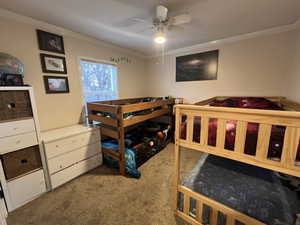 Bedroom with ceiling fan, carpet floors, and ornamental molding