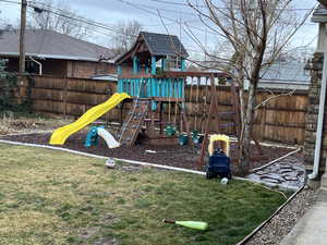 View of jungle gym with a lawn and fence.  It all stays!