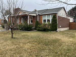 View of front of home featuring brick siding, a front lawn, and fencing