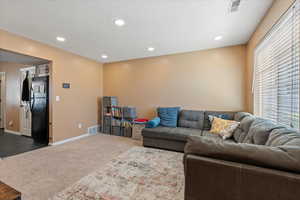 Living area with dark colored carpet, visible vents, baseboards, and recessed lighting