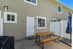 Doorway to property featuring stucco siding, fence, outdoor dining area, and a patio