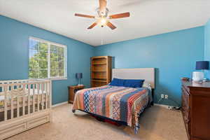 Carpeted bedroom with ceiling fan and baseboards