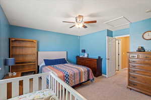 Bedroom featuring attic access, carpet flooring, and ceiling fan