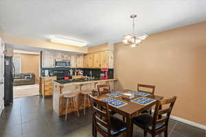 Kitchen with stainless steel microwave, electric range, decorative backsplash, light brown cabinetry, and a peninsula