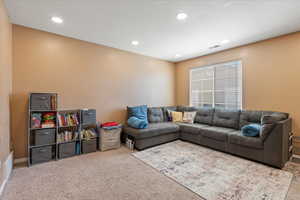 Carpeted living room with visible vents and recessed lighting