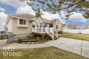 View of front of house with a front lawn, fence, roof with shingles, stucco siding, and a patio