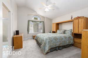 Bedroom featuring light colored carpet, baseboards, lofted ceiling, and ceiling fan