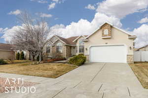 View of front of home with stone siding, driveway, and fence