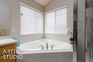 Bathroom with vanity, a garden tub, and lofted ceiling