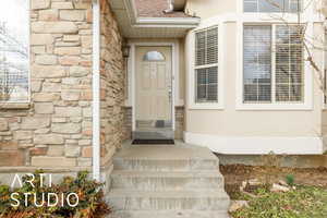 Doorway to property featuring stone siding and roof with shingles