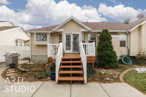 View of front of property with stairs, fence, roof with shingles, and stucco siding