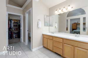 Bathroom featuring tile patterned floors, vaulted ceiling, double vanity, and a sink