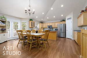 Dining area with a chandelier, vaulted ceiling, recessed lighting, and wood finished floors