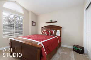 Carpeted bedroom featuring baseboards and vaulted ceiling