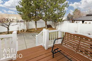 Wooden terrace with a patio and a fenced backyard